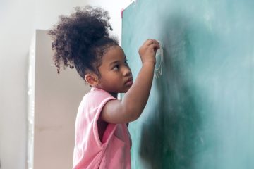 Kid write on chalk board. Back to school. Schoolchild in class. Happy kid writing green blackboard.
