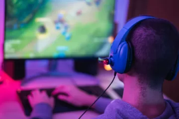 Autistic Teenagers and internet gaming, photo showing an adolescent wearing headphones playing a computer game in front of a screen